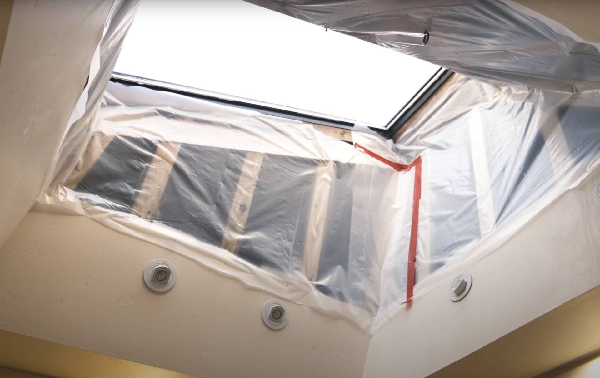 Water damage restoration area with protective plastic sheeting and professional equipment for containment and drying