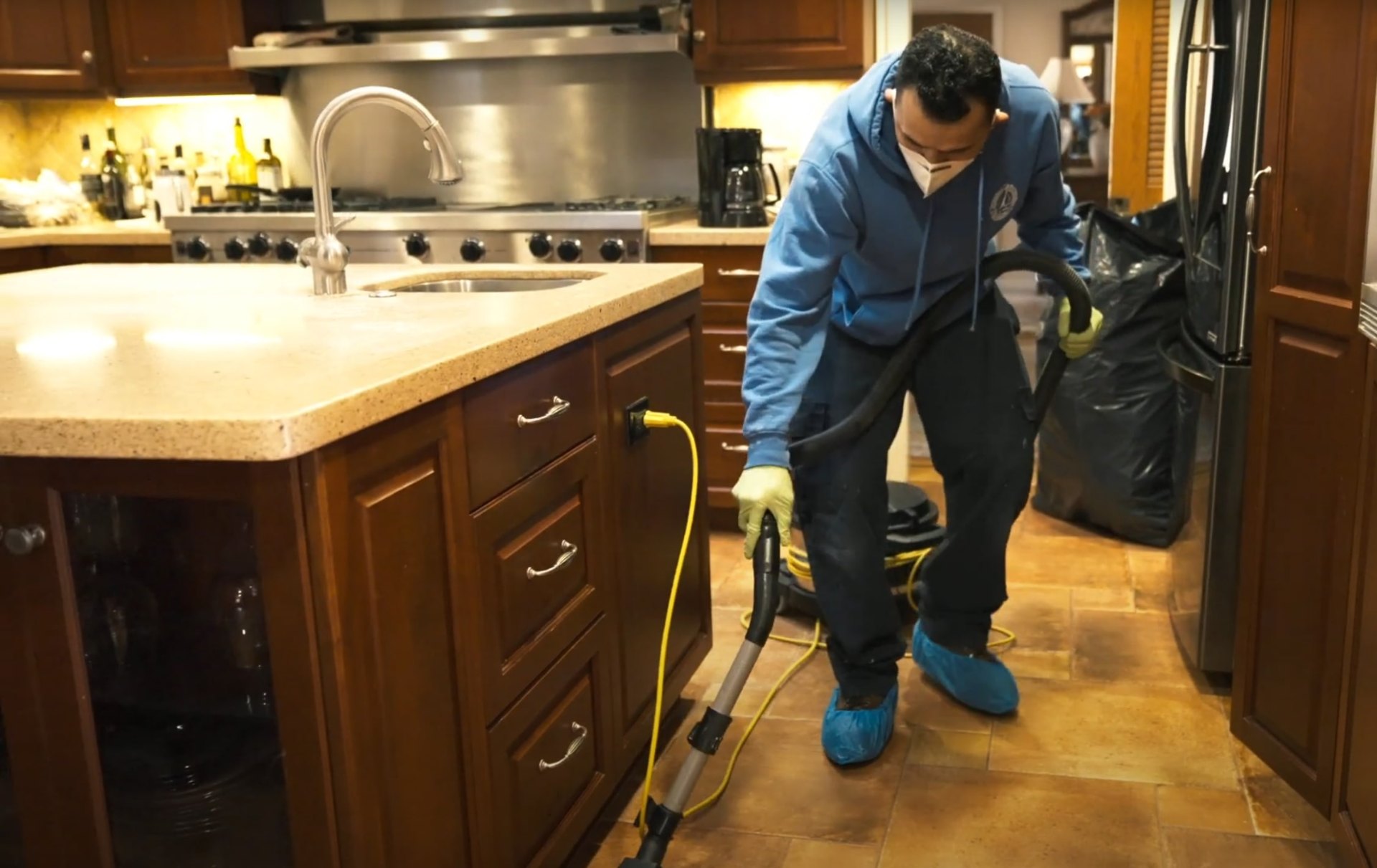 Water damage restoration professional cleaning and extracting water from kitchen with industrial equipment